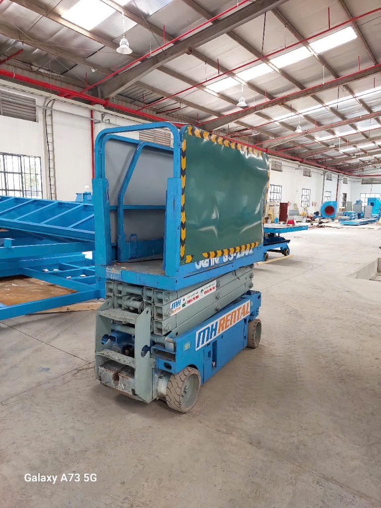 Xe cắt kéo màu xanh cạnh vật tư trong nhà xưởng Chí Linh