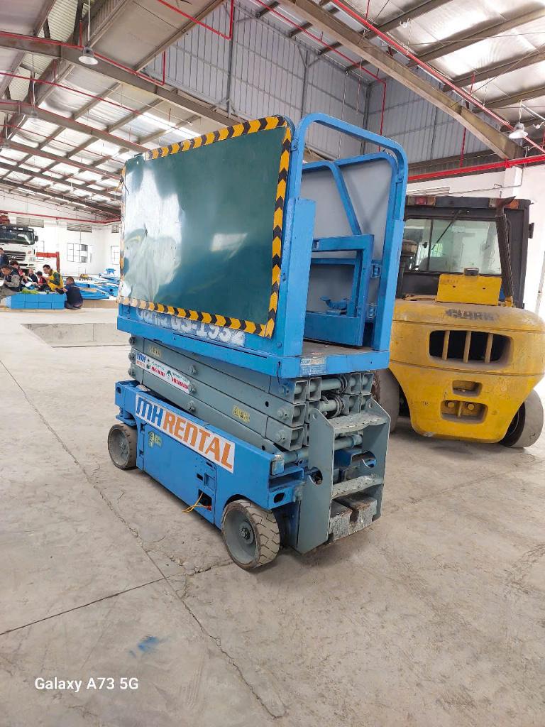 Xe cắt kéo màu xanh bên cạnh xe nâng hàng trong nhà xưởng Chí Linh