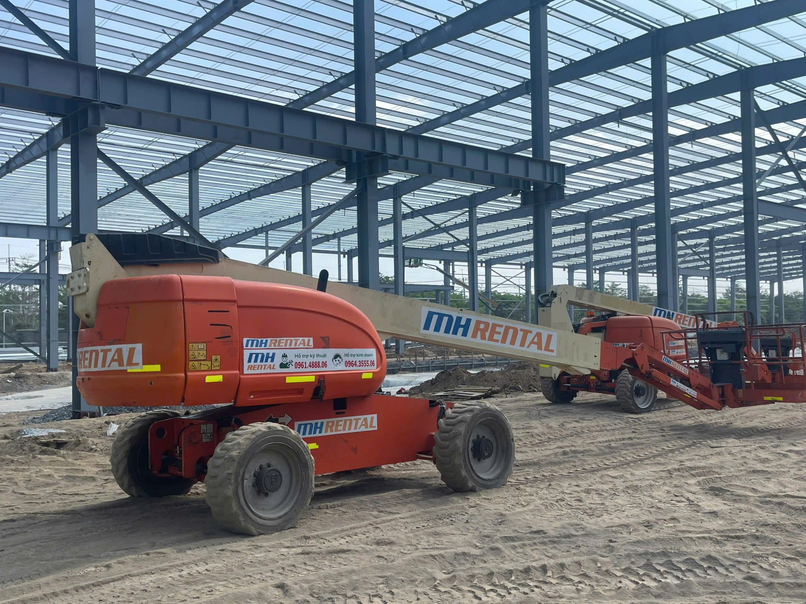 Hai xe boom lift hạ cần trong nhà xưởng Advance tại Tiền Giang
