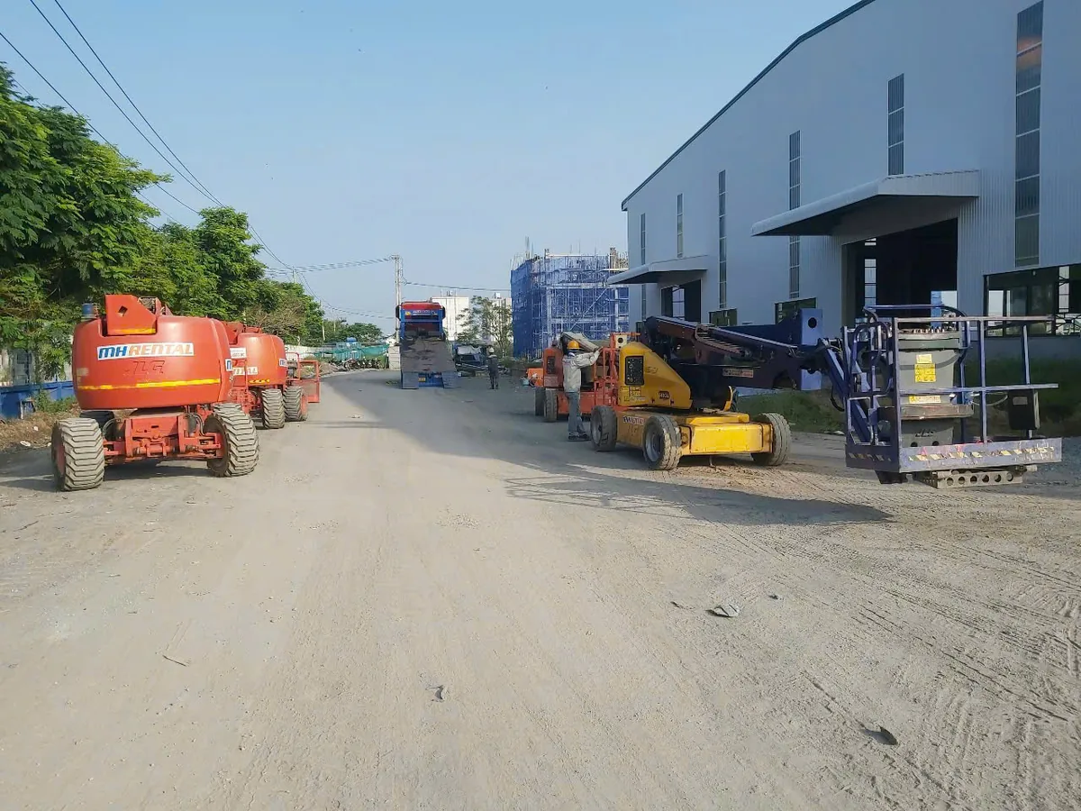 Các xe boom lift MH Rental trên đường cạnh nhà xưởng trong hồ sơ Hòa Phát Cần Đước
