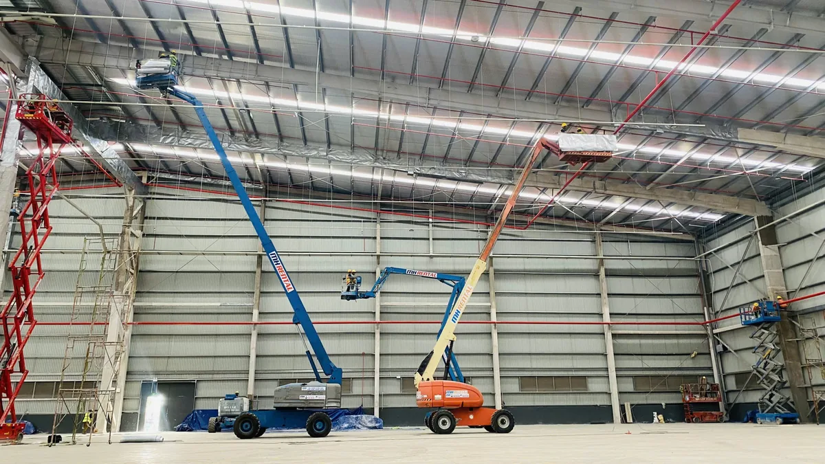 Các xe boom lift MH Rental cùng xe cắt kéo bên trong kho TBS Tân Vạn